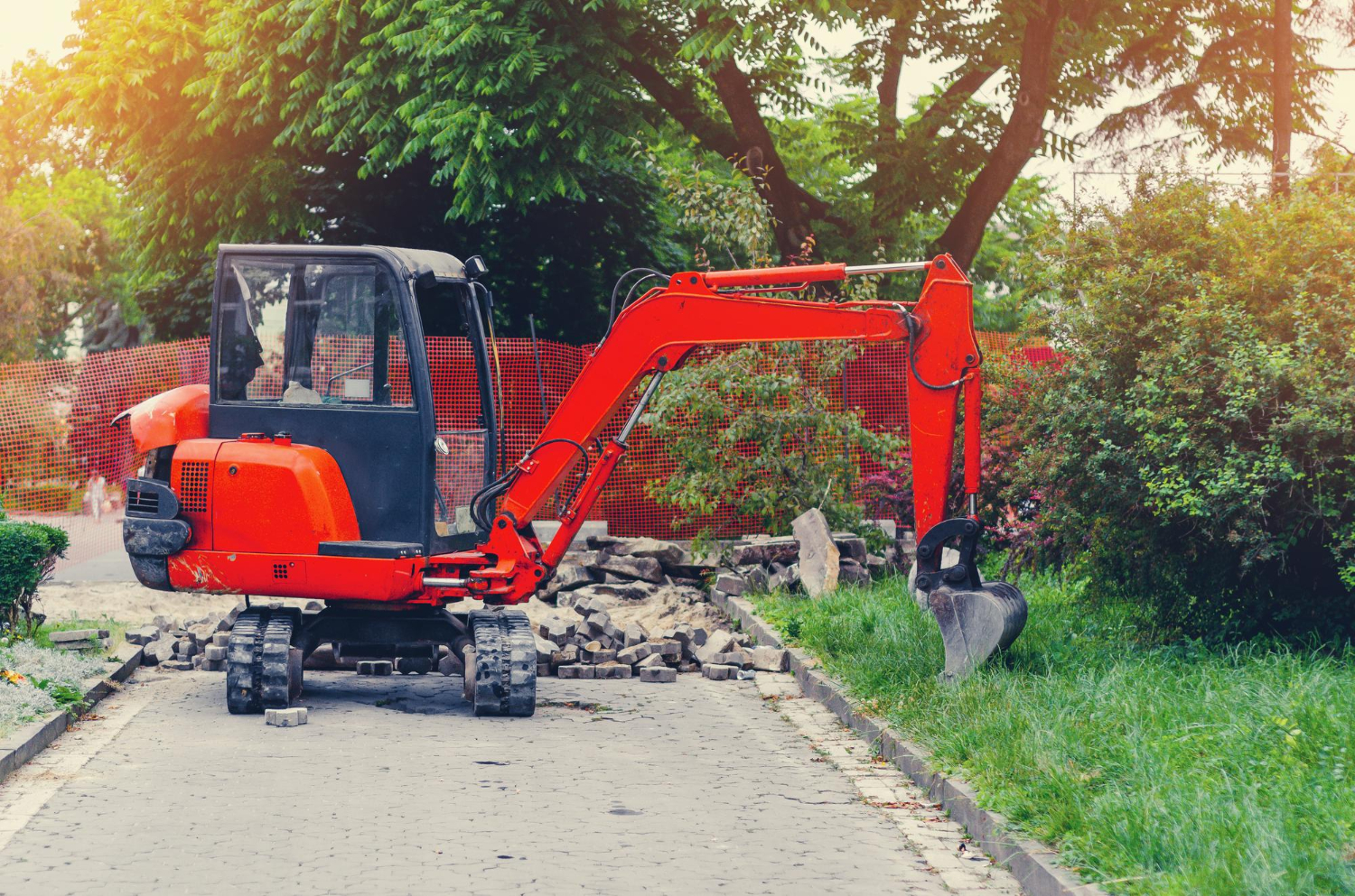 Petite excavatrice sur le trottoir près de la réparation de la pelouse